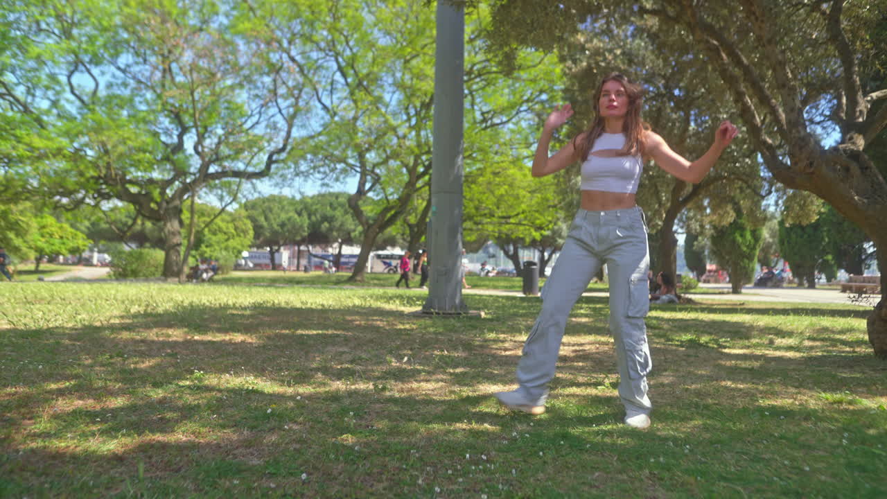 una mujer joven bailando en un parque.