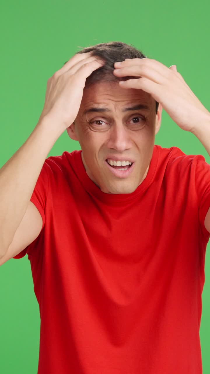 Man expressing worry about hair loss on green screen