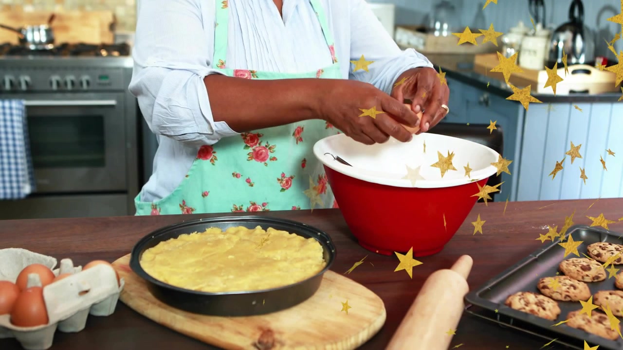 Senhora pegando ovo, quebrando em tigela vermelha para assar torta enquanto estrelas douradas destacam as mãos