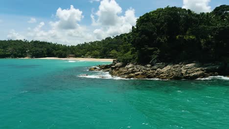 4K-Cinematic-nature-aerial-footage-of-a-drone-flying-over-the-beautiful-beach-of-Surin-in-Phuket,-Thailand-on-a-sunny-day