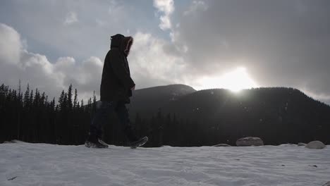 silhouette of a man walking through shot with snow and mountains in background