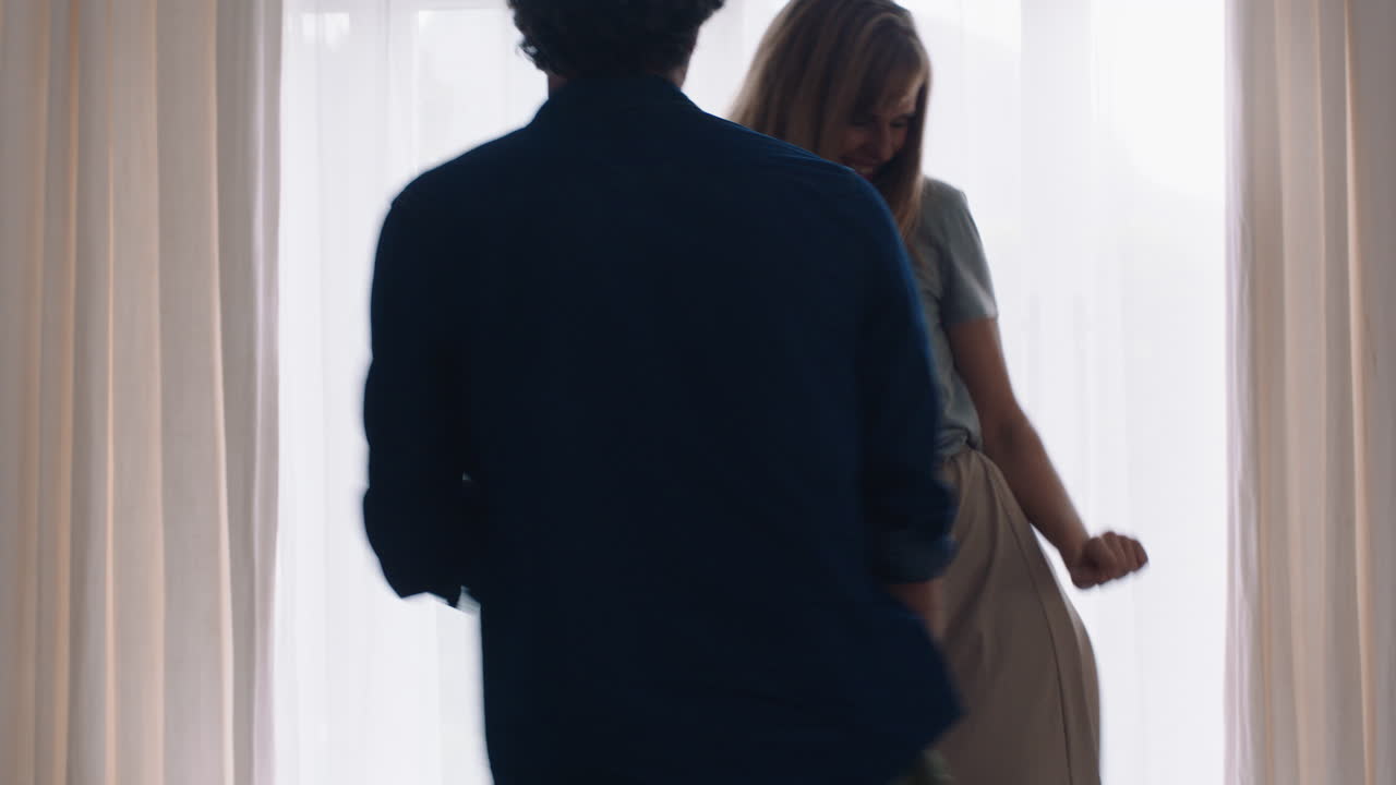 행복한 젊은 커플이 집에서 함께 춤을 추고 축하하고 즐거운 주말을 보내며 웃으며 거실에서 재미있는 춤을 즐기고 성공적인 관계 축하 4k 영상