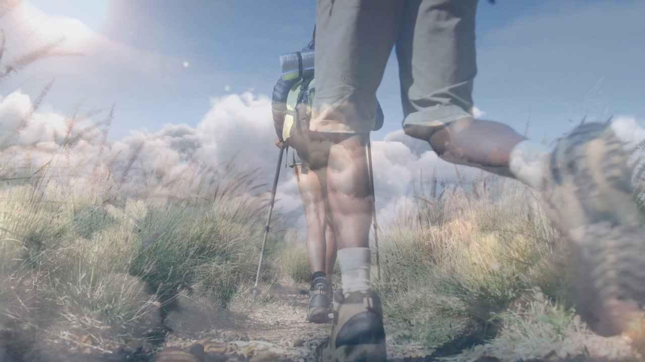 Two hikers trekking along grassy trail, showing animated fitness stats, map overlay, backpack icon