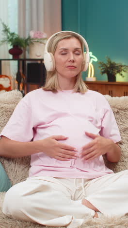 pregnant woman meditation headphones ocean waves sound calm posture hands on belly focus balance zen