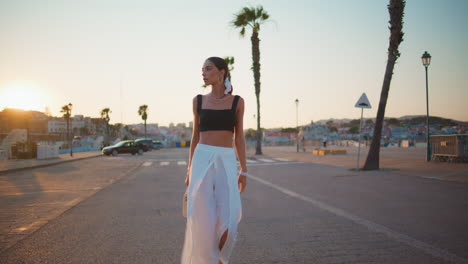 stylish woman walking on a city street at sunset