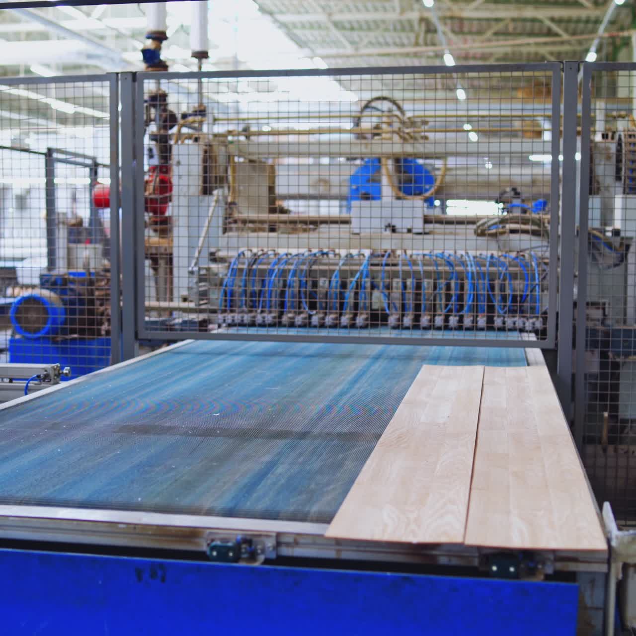 Modern wooden industry. Robotic machine working on a factory for producing wooden laminate. Production line with parquet panels.