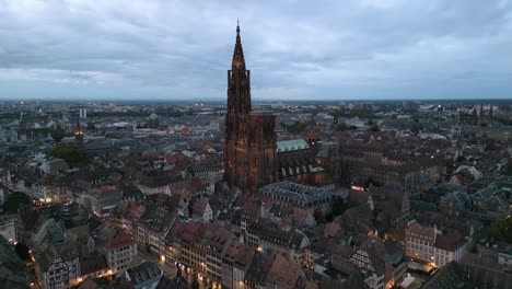 aerial zoom in twilight view of strasbourg cathedral illuminated against the backdrop of the historic city center
