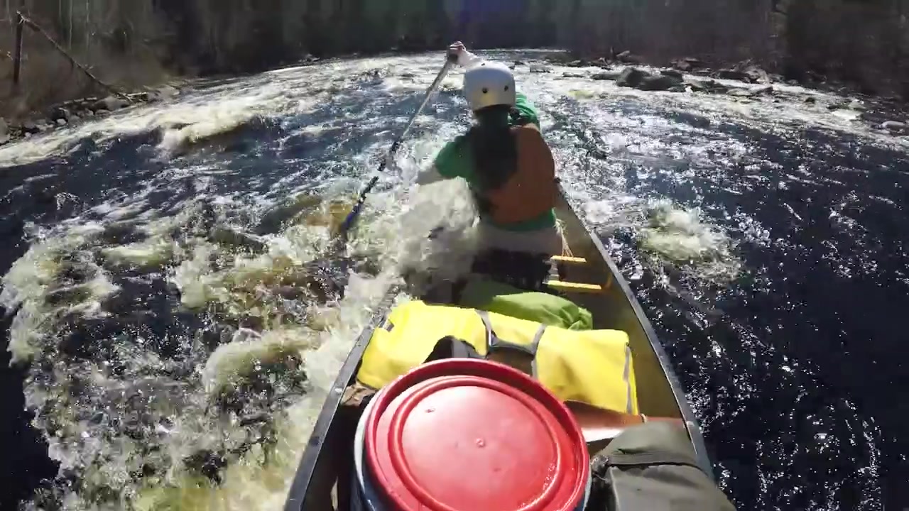 Ampia inquadratura di canoa su rapide di acque bianche selvagge su un fiume con una canoista