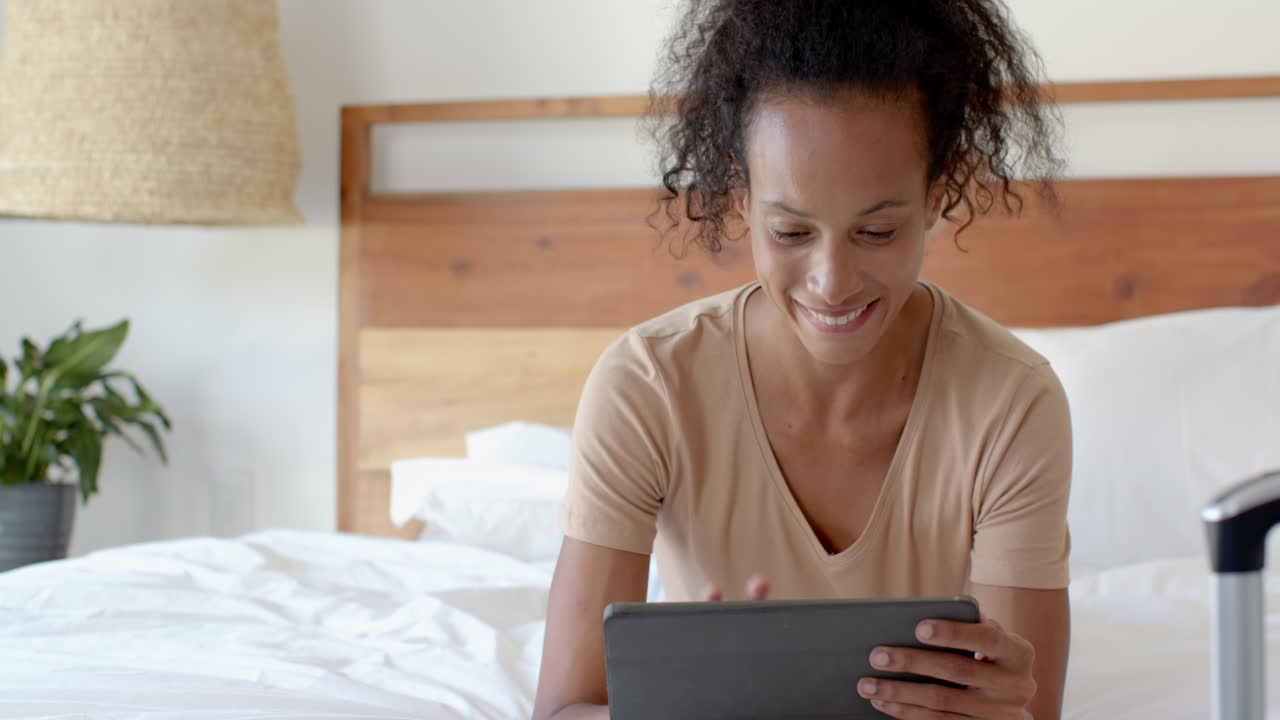 woman using tablet in bed, focusing on work at home