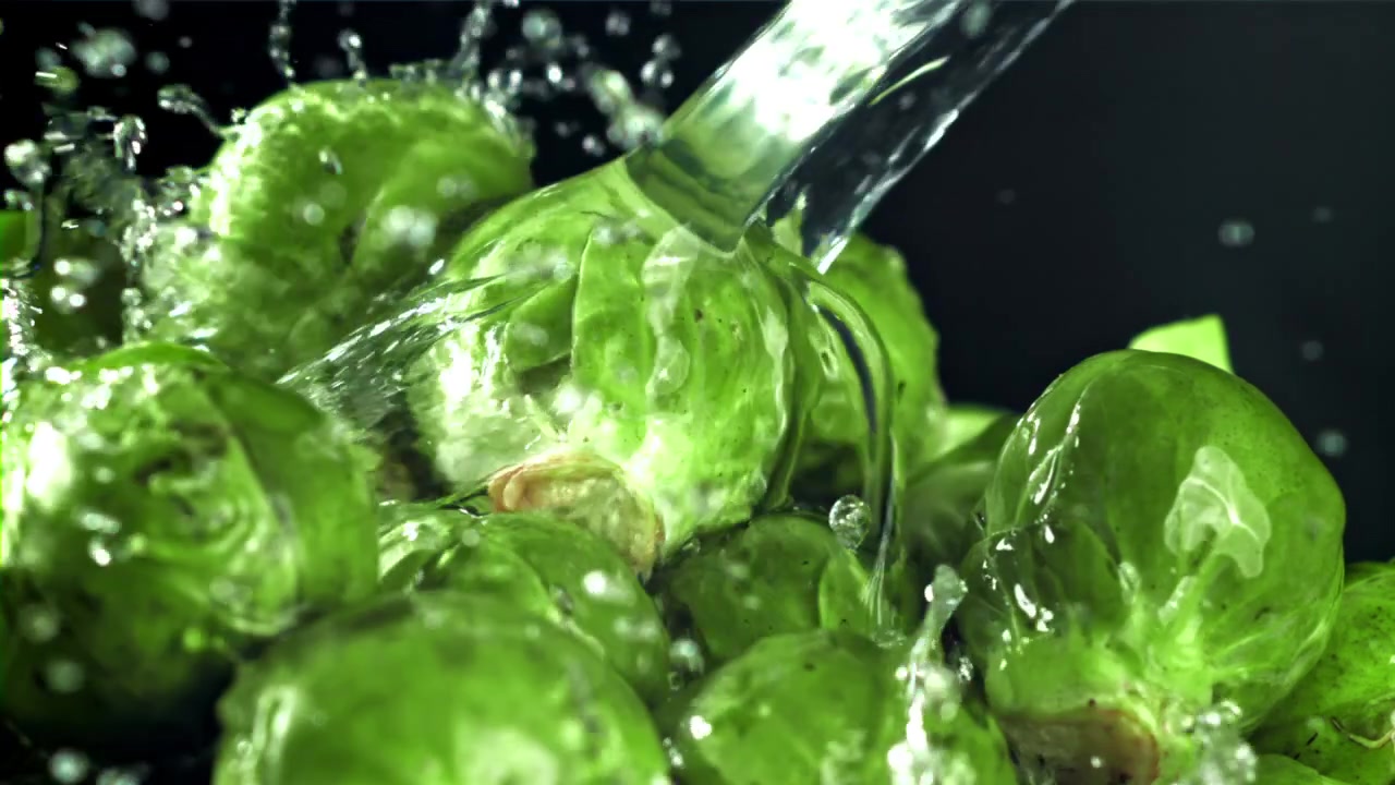 Schizzi d'acqua su cavolini di Bruxelles freschi e verdi al rallentatore