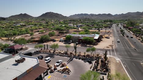 lowering drone shot of a parking lot in arizona decorated with cactus and clay sculptures