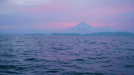 pink sunset in mountain landscape on horizon and evening sea waves