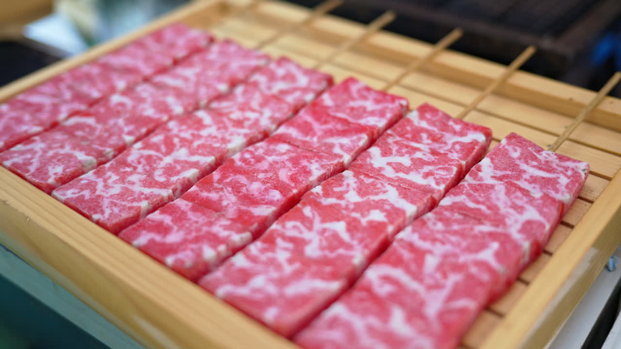 Close up of multiple pieces of Wagyu beef on a wooden tray at a street food market in Japan