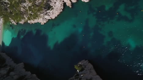 The-Calanque-d'En-Vau-is-a-beach-between-very-steep-and-rugged-cliffs-near-Cassis,-France---aerial-reveal-in-vertical-orientation