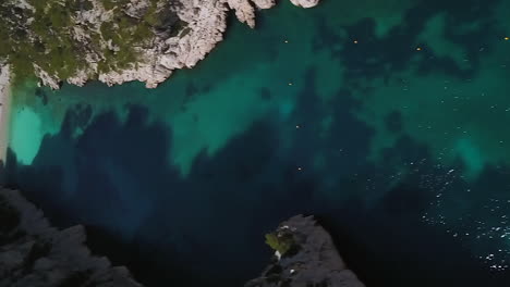 the calanque d'en-vau is a beach between very steep and rugged cliffs near cassis, france - aerial reveal in vertical orientation