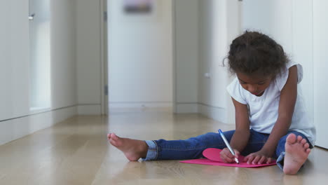 chica hispana sentada en el suelo haciendo tarjetas para el día de la madre