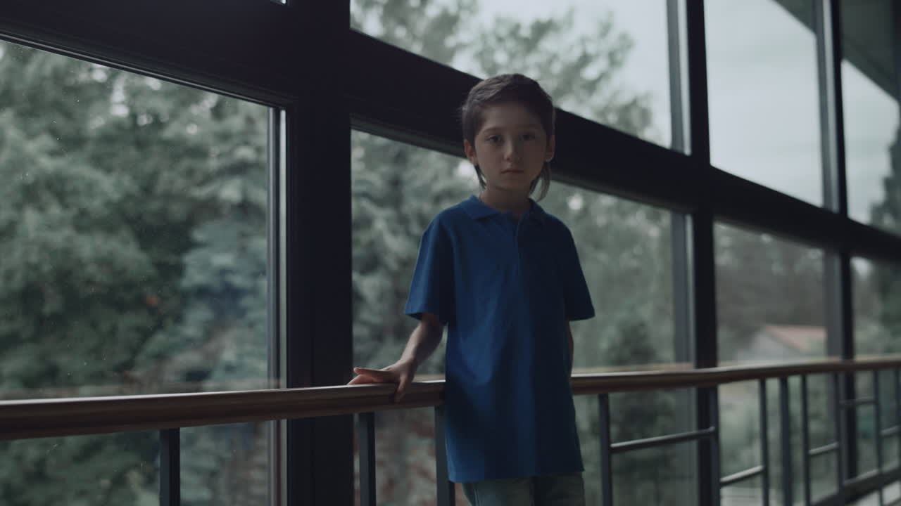 파노라마 창문 앞에 혼자 서 있는 슬픈 소년. 십대 학생이 외로움을 느다.