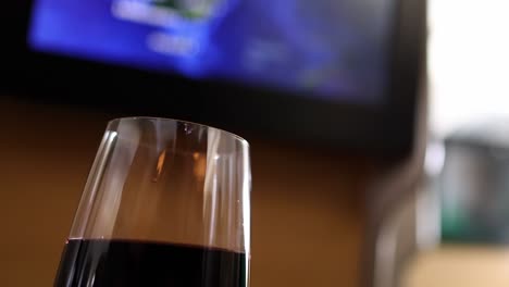 a close-up of a wine glass with a blurred screen in the background, creating a relaxed ambiance.