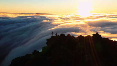 aerial orbit, drone shot around hikers, on the summit of the on mount hassell mountain, above clouds, during sunset, in west australia