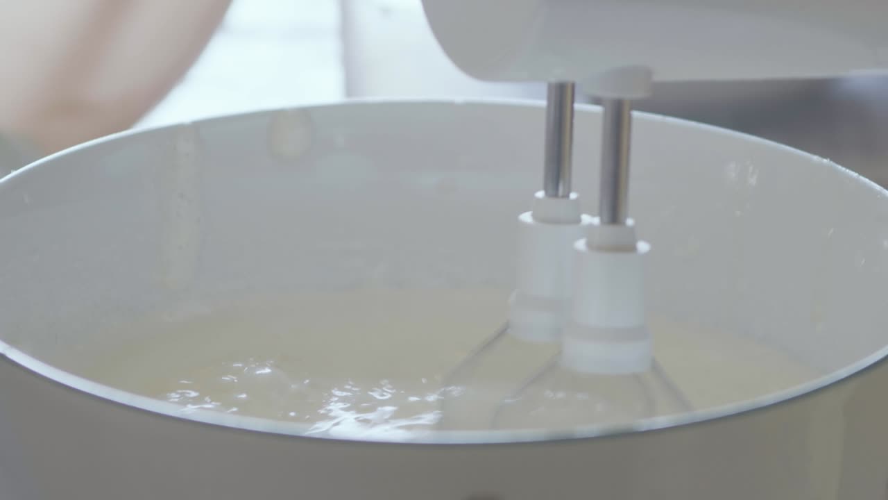 detalle de un momento de elaboración de pasteles: una anciana está mezclando los ingredientes para un pastel de chocolate con látigos eléctricos