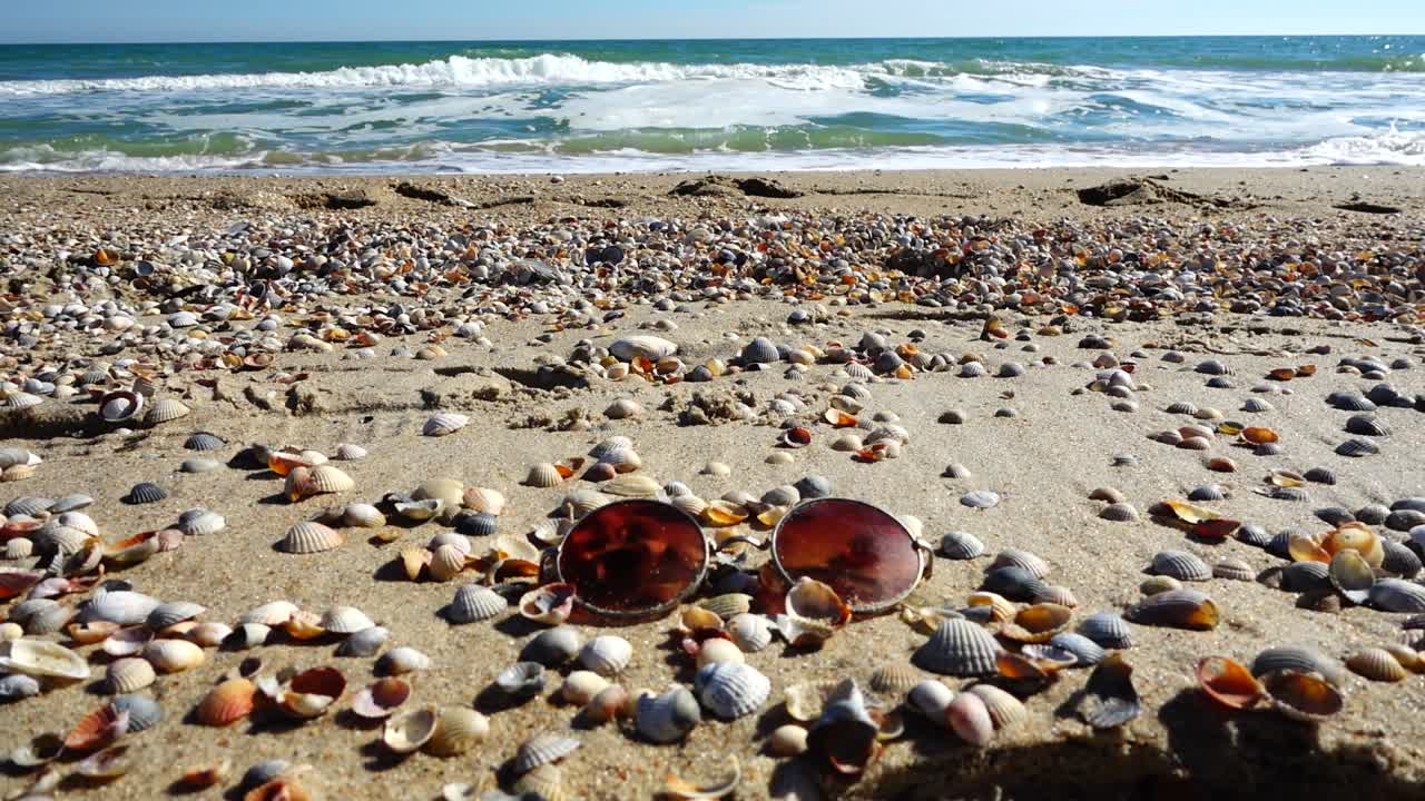 Sunglasses on the sandy beach. Slow motion