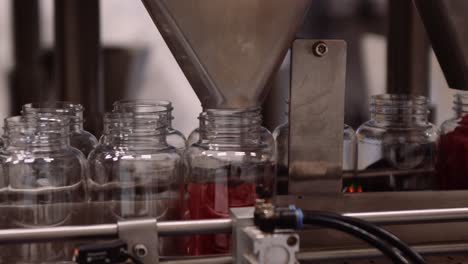 clear bottles being filled with red multivitamins - automated process