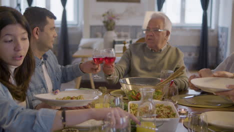 familia feliz sentada a la mesa en el comedor, hablando juntos y disfrutando de la comida en casa 1