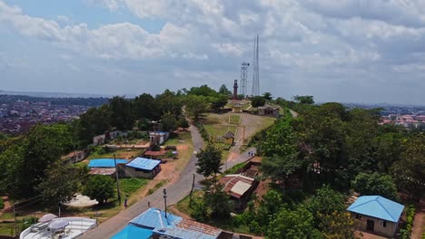 drone slowly flying towards a beautiful park with the historical bowers tower in the distance. filmed in ibadan, nigeria, africa
