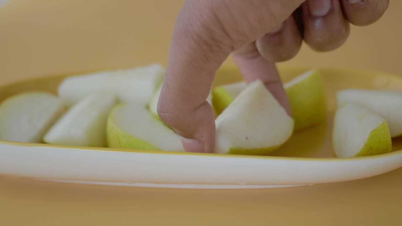 Hand picking a sliced pear from a plate
