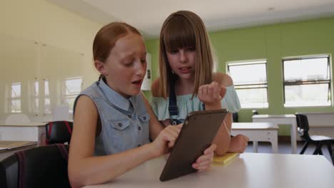dos niñas que usan una tableta digital en la clase