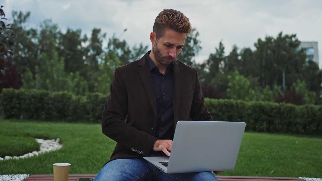 Businessman working on laptop in a park