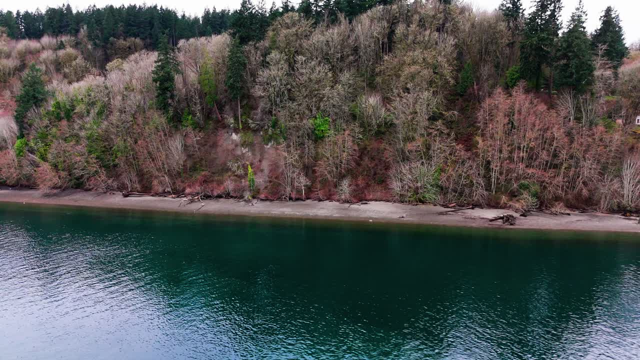 Aerial cinematic view of coastal beach on a cloudy day in the Pacific Northwest Gig Harbor, Washington State