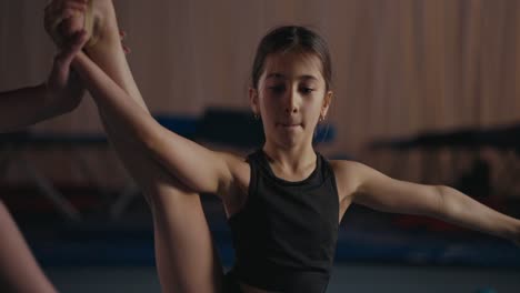 young gymnast practicing a stretch with her coach