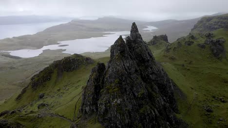 4k-aerial-drone-footage-close-up-of-rocks-at-old-man-of-storr-isle-of-skye-loch-lake-and-fog-in-background-scotland