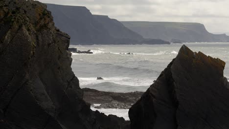 Extra-wide-shot-between-two-big-rocks-with-sea-in-background-at-Hartland-Quay,-Stoke,-Hartland,-Bideford