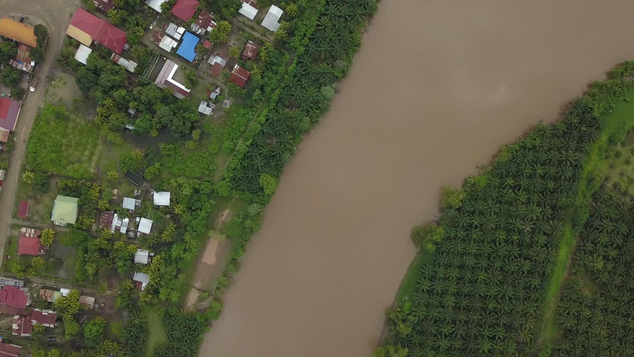 Top birdseye view of big river next to a plantation and a small village