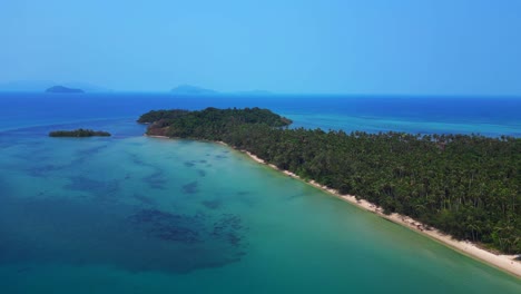 palm trees bordering ao soun yai beach in koh mak, thailand, with turquoise water. majestic aerial view flight wide orbit overview drone
