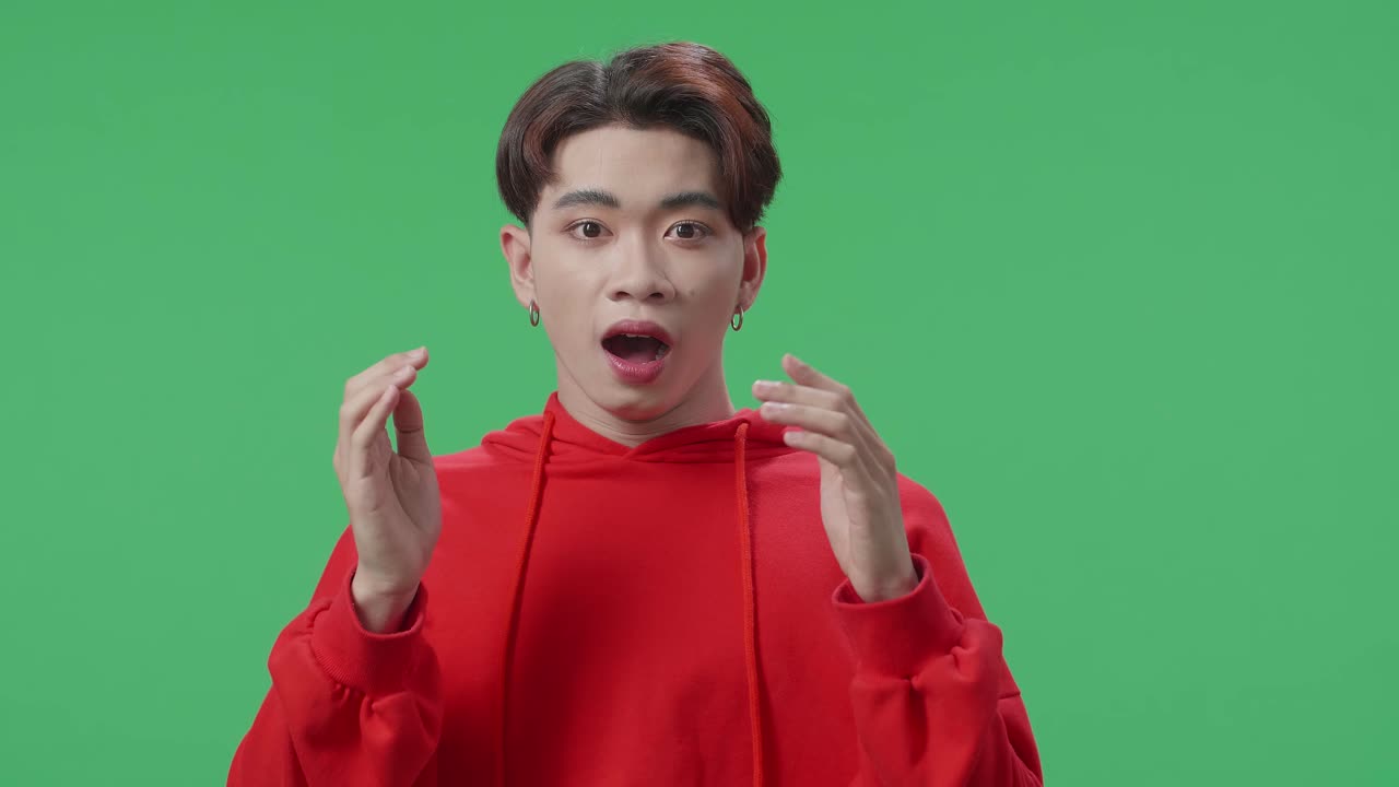 Portrait Of A Young Asian Transgender Male Opening Her Eyes With Palms And Becoming Surprised In The Green Screen Studio