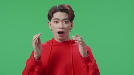 portrait of a young asian transgender male opening her eyes with palms and becoming surprised in the green screen studio