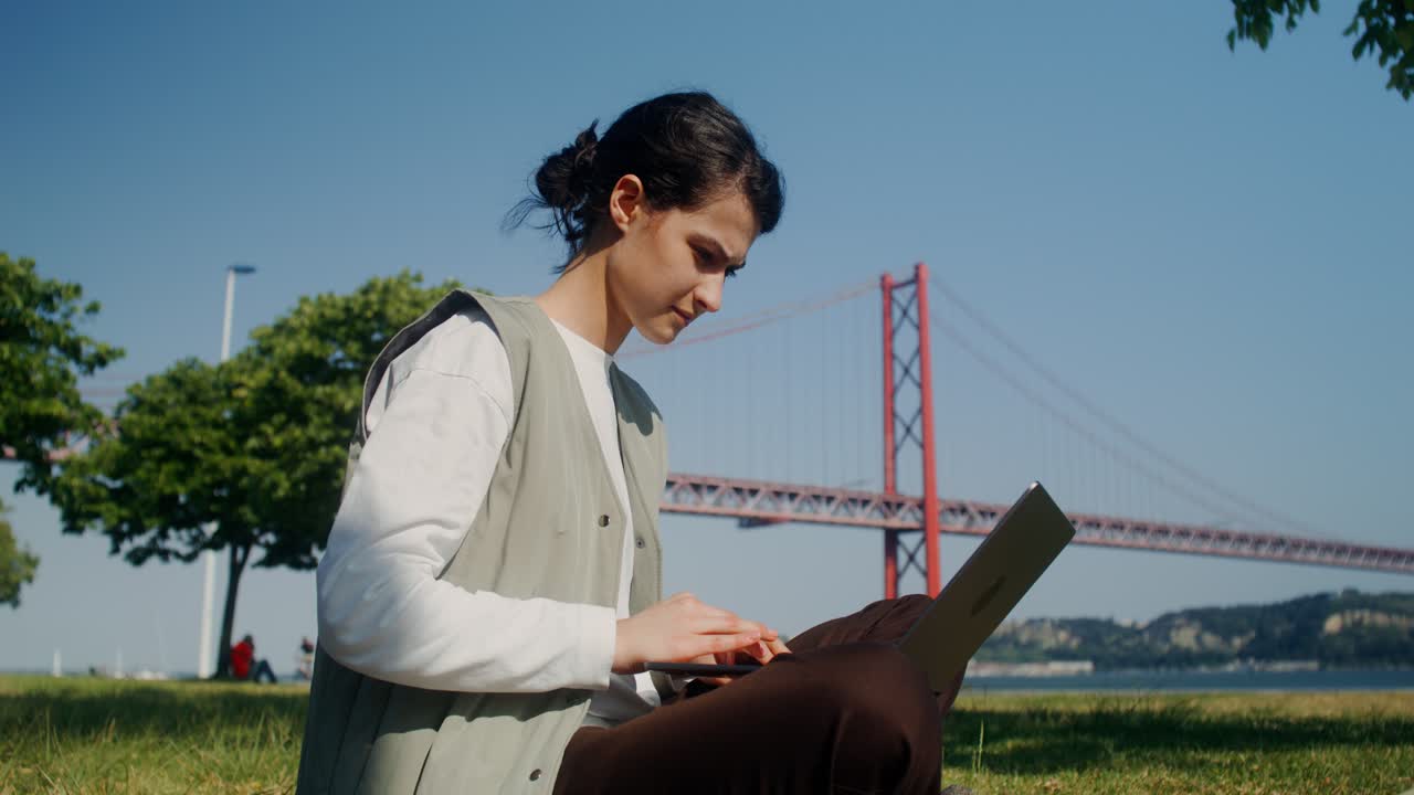 다리 에 있는 공원 에서 노트북 을 사용 하고 있는 여자
