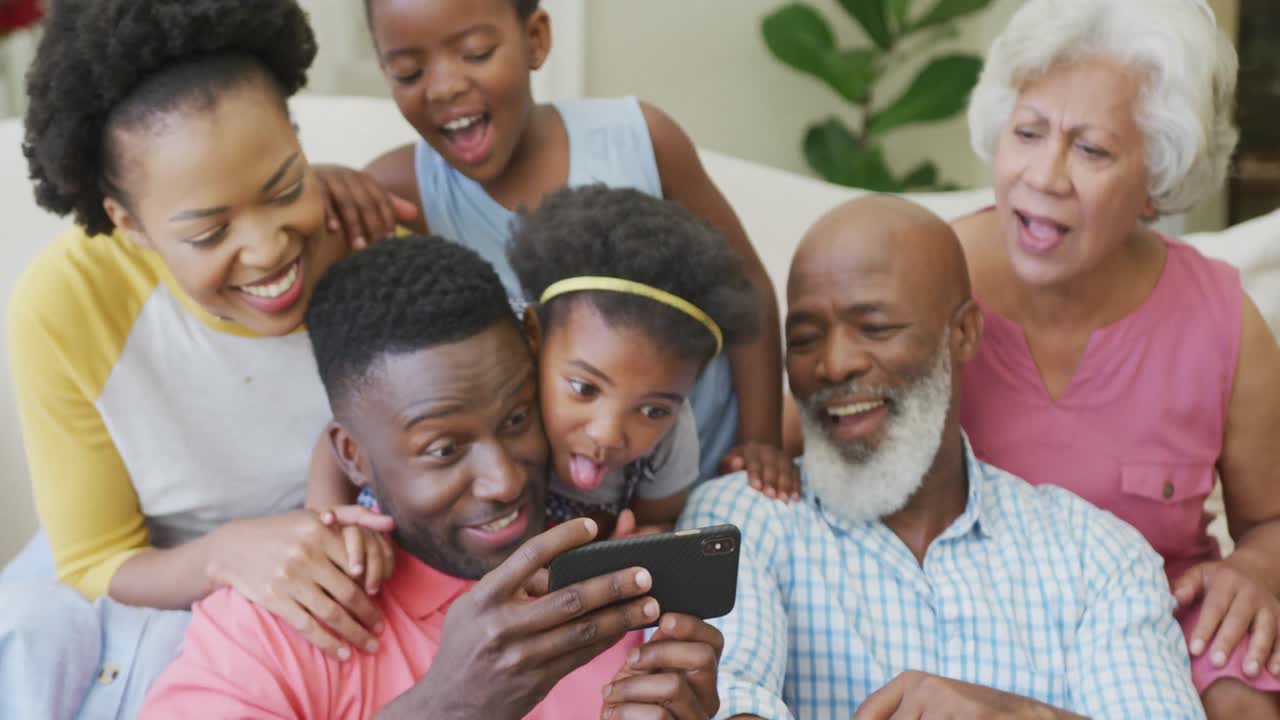Happy african american family sitting and using smartphone in living room