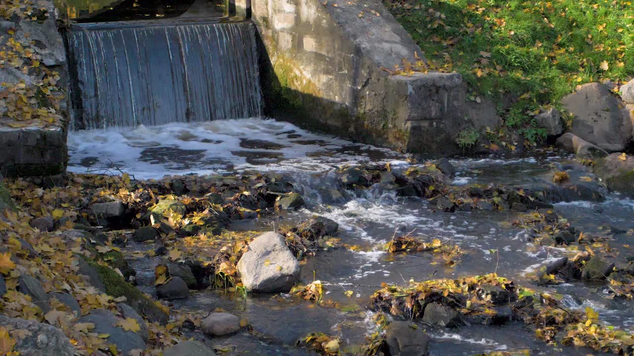small waterfall in the park during fall season in autumn
