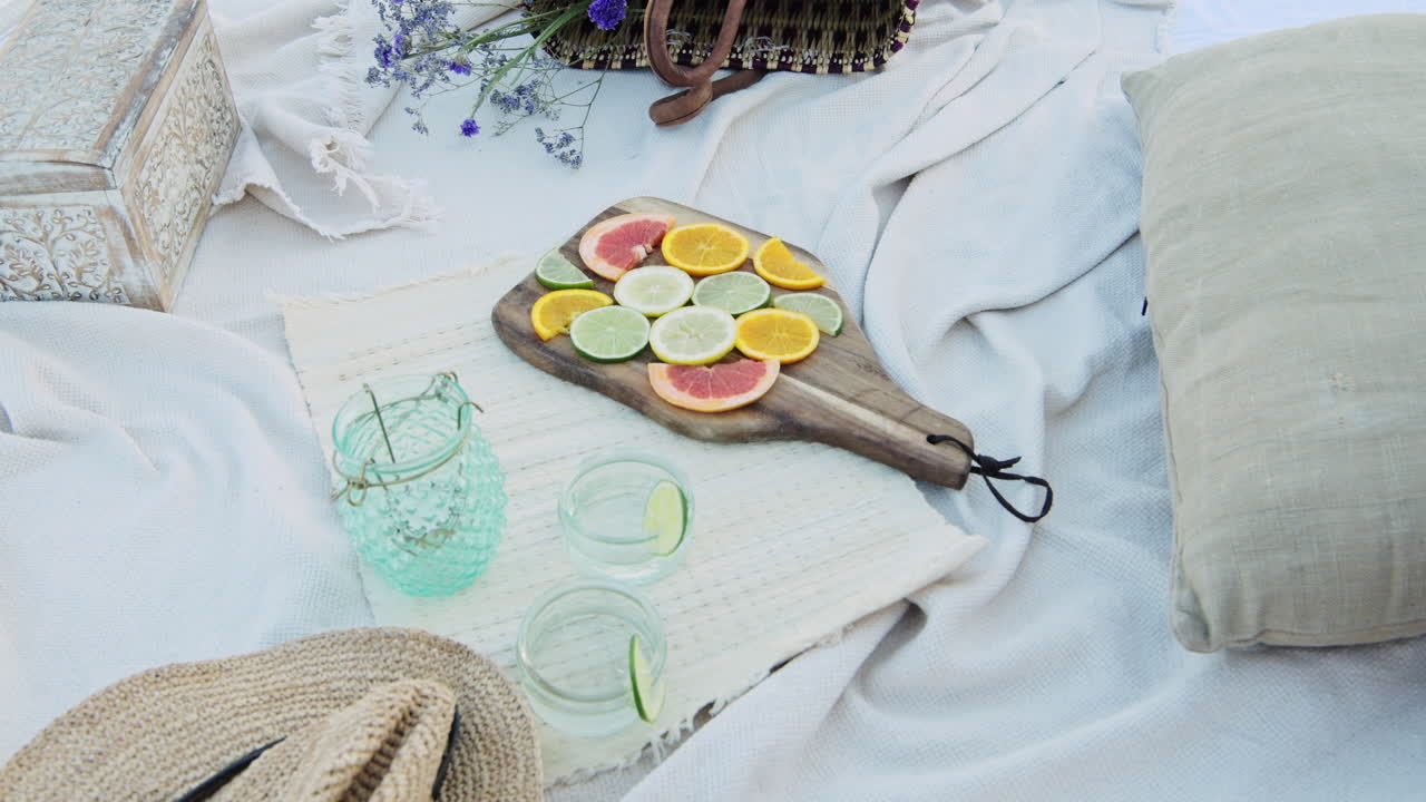 Taking a wooden picnic board with beautiful citrus fruit slices of orange, lemon, grapefruit and lime - A perfect luxury romantic picnic set up