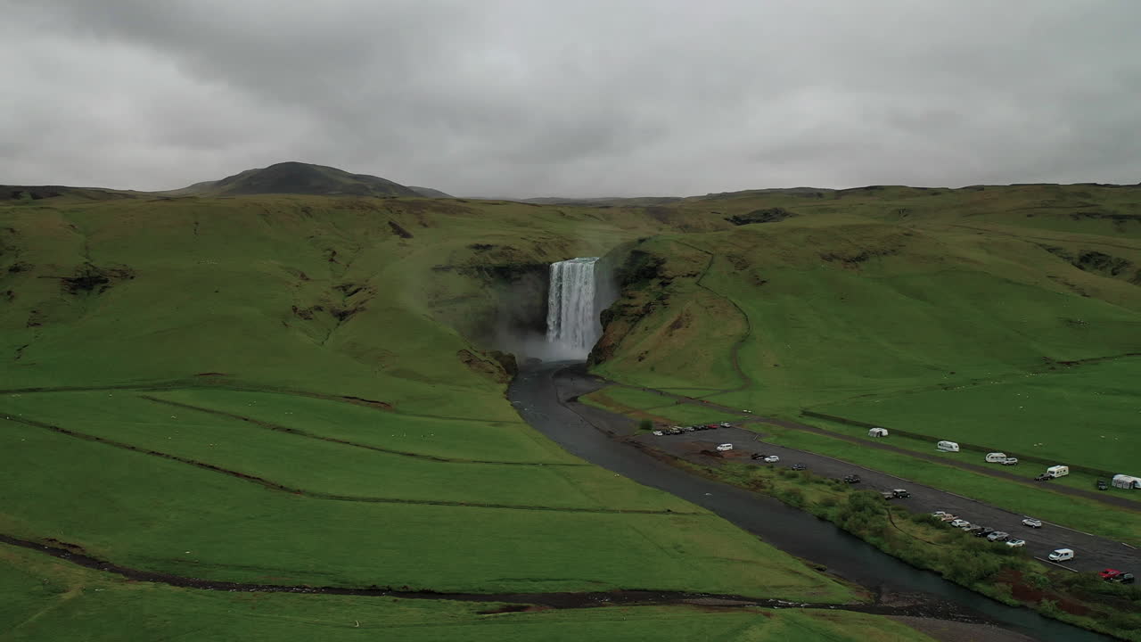 drone volando hacia skogafoss, una hermosa cascada en el río skoga, rodeada de un paisaje exuberante en el sur de islandia - antena