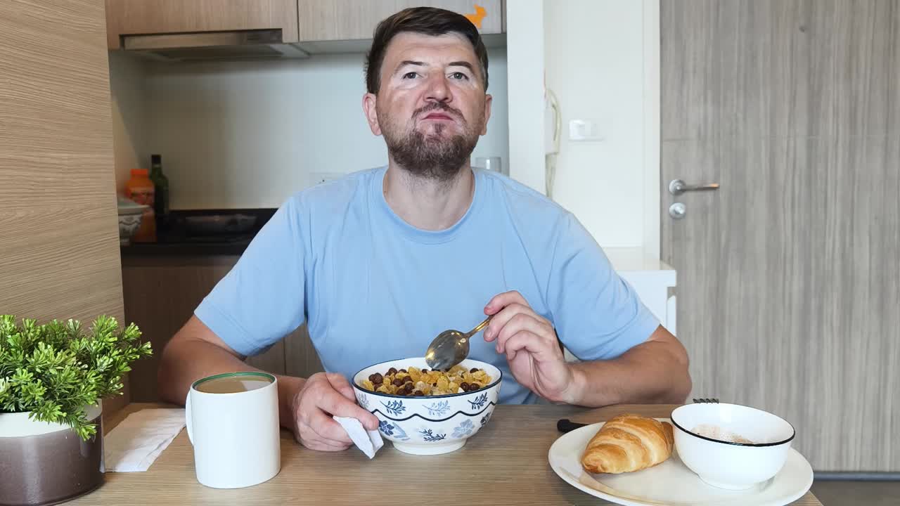 Man eating cereal with a croissant for breakfast