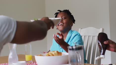 Afroamerikanischer-Junge-Lächelt,-Während-Er-Zusammen-Mit-Seiner-Familie-Zu-Hause-Frühstückt