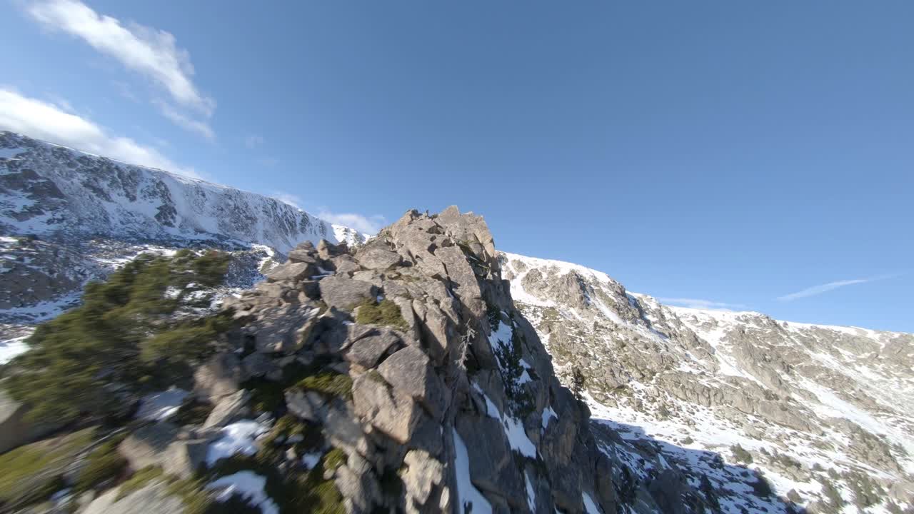drone fpv aéreo acrobático volando sobre montañas rocosas cubiertas de nieve
