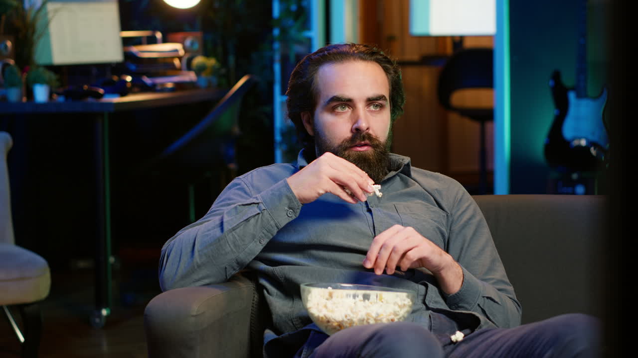 hombre en casa sorpresa por el final de la película, no puede creer sus ojos, dejando caer palomitas de maíz