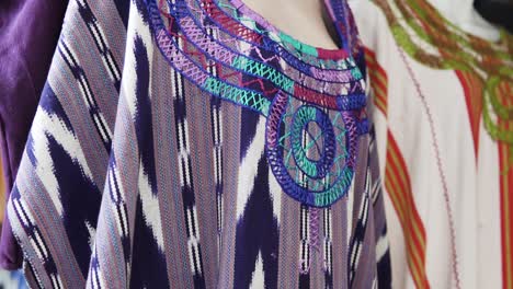 Tilt-down-shot-of-showing-colorful-designer-huipil-blouses-indigenous-displayed-in-a-shop-in-Guatemala,-Central-America-ay-daytime