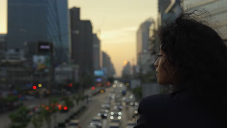 woman contemplating cityscape at sunset